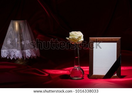blank mourning frame, with goldene chalice and white rose on dark red background