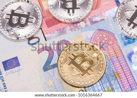 Golden and silver bitcoin coins on euro banknotes 