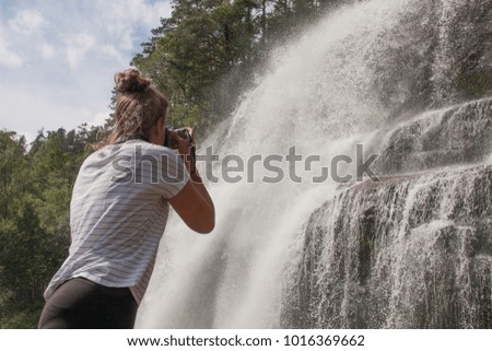 Girl is photographing a waterfall in Norway