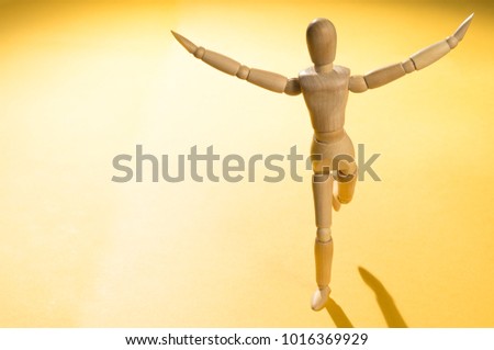 Human figurine runs on yellow background.
