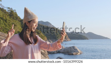Woman taking selfie on cellphone with the sea background 