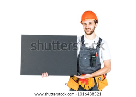 Full length portrait of a male construction worker with a white blank banner over a white wall background. repair and construction. Isolated over white background
