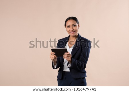 Beauty at work, side view of confident young hispanic woman holding digital tablet while standing against pink background