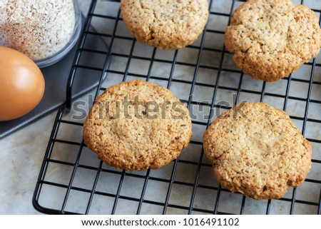 Glutenfree homemade oatmeal cookies, oats, egg on cooling rack. Selective focus. Toned photo.