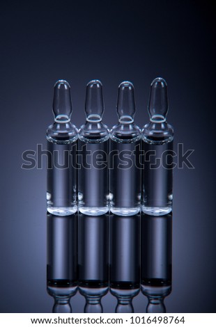 photo of  ampoules with medicine remedy on a dark background with a bright spot