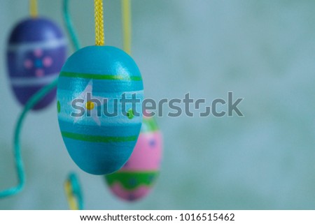 close up blue purple painted Easter eggs, hanging on yellow rope against flamed background