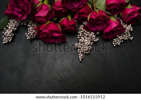 Gothic wedding flowers decor. Dark red or burgundy roses with silver adornment on black background. Bold, daring ,alternative ,and luxury reception party flower arrangement