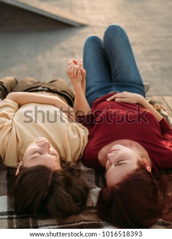 Lesbian couple in love relax. Laying together holding hands dreaming of future and enjoying their relationship. Tenderness intimacy