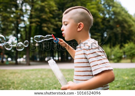 Rapt little boy blows bubbles in the park. Delights of childhood.