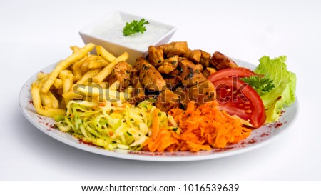 A close shot on a spicy dish of pieces of fried chicken seasoned with tomatoes parsley and green leaves of lettuce