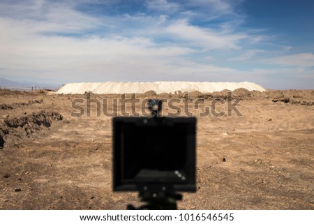 An out of focus pinhole camera pointed towards a flat white mining waste deposit in the Atacama desert. A photographer's camera produces an analog photograph on 4x5 large format film.