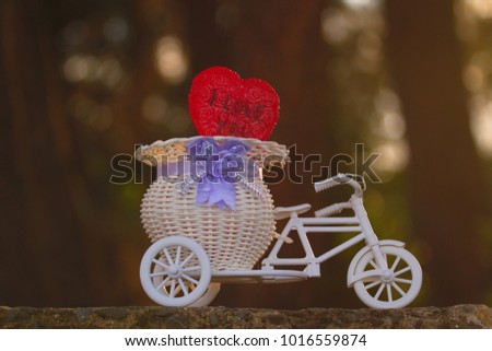 Conceptual photo for Valentine's day: A toy of small bicycle with love shape and text "I Love You" on nature background