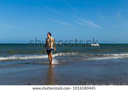 A man walks in the water, on a summer day at Guadalupe beach, city of Sirinhaém, Pernambuco state, Brazil.