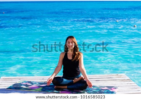Young woman doing yoga mudras and meditating  on the beach. Early, chilly and sunny morning. Outdoors yoga. Healthy Living.