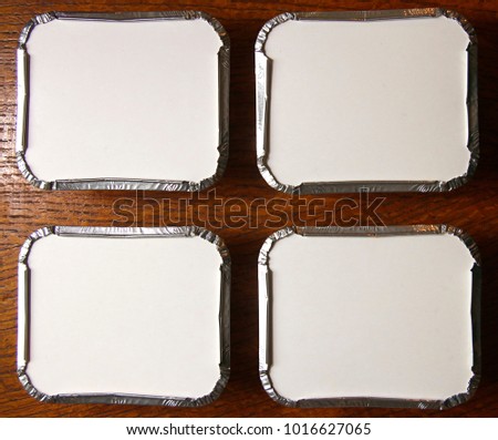 Four silver foil fast food cartons on a wooden table - useful as a takeaway slide background for your powerpoint presentations