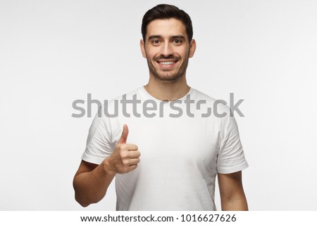 Young optimistic man isolated on grey background showing thump up with positive emotions of content and happiness. Concept of satisfaction with quality and recommendation Royalty-Free Stock Photo #1016627626