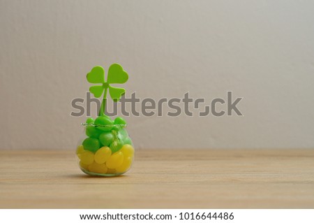 A clover displayed in a pot that is filled with yellow and green jellybeans