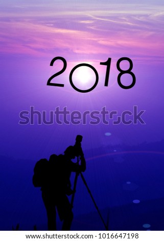 Silhouette of photographer taking picture of landscape  with tripod during beautiful sun rise with 2018 text,purple and blue tone,copy space.