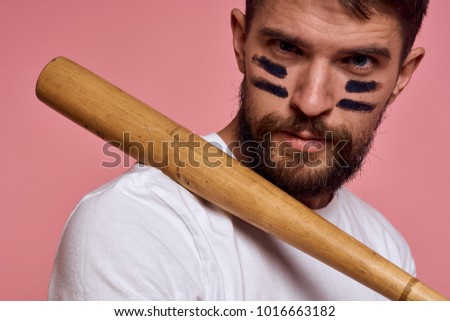 man with a beard is holding a baseball bat on a pink background                              