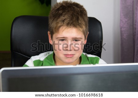 Obese little boy sitting at the computer.