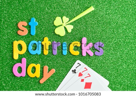 Happy saint Patricks day in colorful letters on a green background with a clover and 777