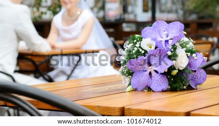 The beautiful wedding bouquet flowers , on a background a newly-married couple. Focus on a bouquet
