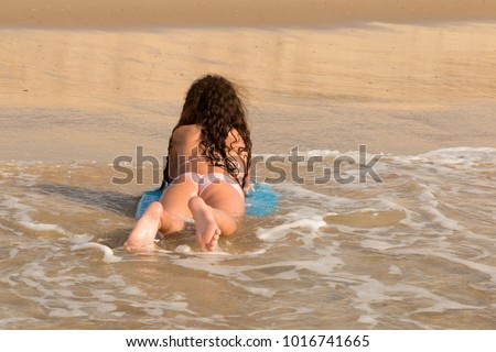 young fit girl lying on bodyboard on sand beach summer
