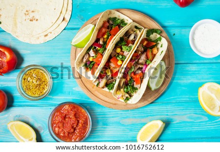 Mexican pork tacos with vegetables on wooden blue rustic background. Top view
