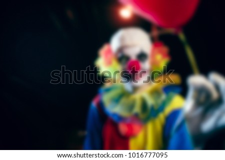 Blurred photo of clown with balloons at night