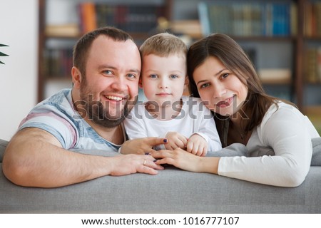 Photo of loving parents and son sitting on gray sofa