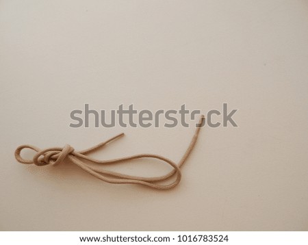 A knotted tan shoe lace laying on a plain background. Macro close up.
