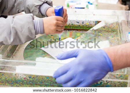 educational games, handcraft, painting concept. close up of two couples of arms of child and man that are working on art project using special equipment for creating abstract backgrounds