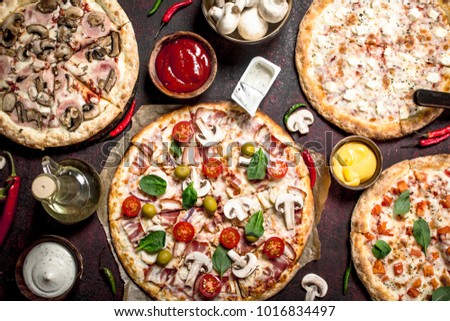 variety of pizzas with sauces. On a rustic background.