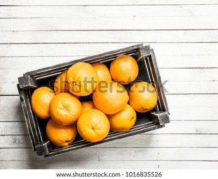 Fresh oranges in a box. On a white wooden table.
