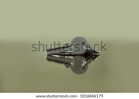 Bunch of three metal house keys lying on the reflective surface with copy space