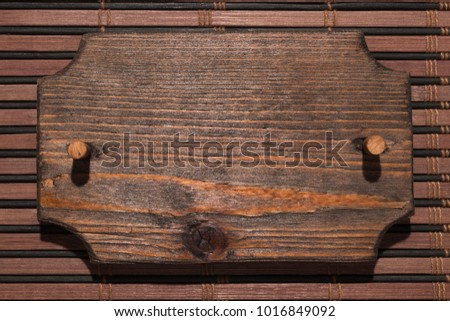 Wooden patterned frame made of wood with a wooden gag is on a bamboo mat. Hard light for hard shadows.