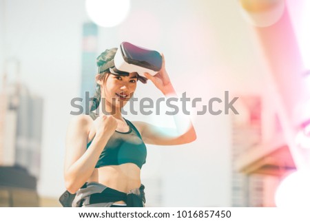 A young beautiful girl in virtual reality glasses makes sport and aerobics in the city. Future technology concept. VR-headset glasses.