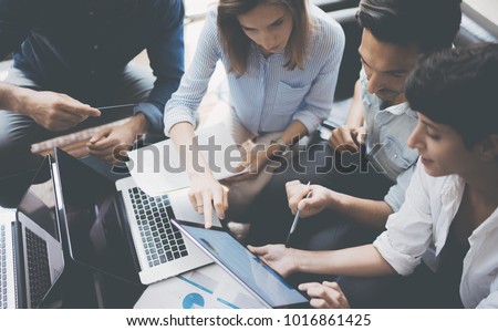 Closeup view of group young coworkers working on mobile laptop computer at office.Woman holding tablet and pointing on touch screen. Horizontal, blurred background Royalty-Free Stock Photo #1016861425