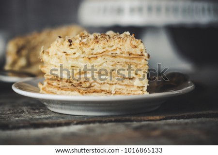cake - Napoleon (cake with white cream is layered) and photos on a wooden table
