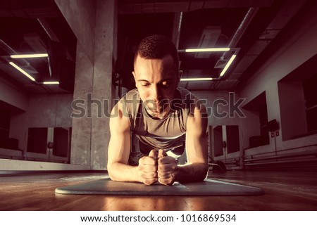 Plank as good abdomen exercise. Toned image. Man exercising lying on the gym mat. in the front view
