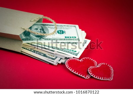 Paper bag with money on a red background. decorative hearts made of red fumirana sewn with a white thread a symbol of a gift for St. Valentine's Day. selective focus. close-up