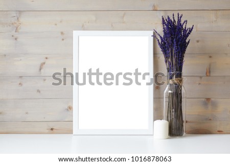 Mother's Day, Women's Day or other suitable holiday card in rectangular photo frame with blank space for your text on white table with lavender flowers bouquet in glass bottle and paraffin candle
