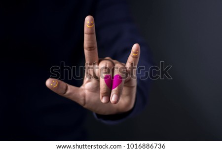 Happiness Love Concept, Midsection Of Man With Colorful Hand Guesture in means "I Love You" with Heart and Smiley Face on Fingers Against Dark Background