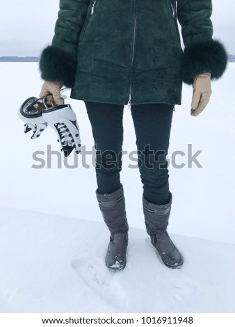 Close up portrait of a woman holding ice skates on a snowy day. Tartu, Estonia.