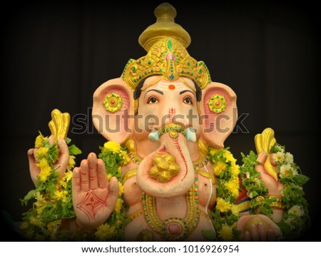 A closeup picture of Hindu foremost God Lord Ganesh (Ganesha / Elephant Head) Idol with colourful flower garlands