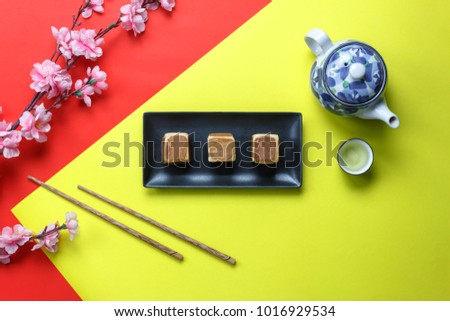 Top view aerial image of arrangement decoration Chinese new year & lunar holiday background concept.Flat lay pink blossom with food & drink on modern red & yellow paper at office desk.Pastel tone.
