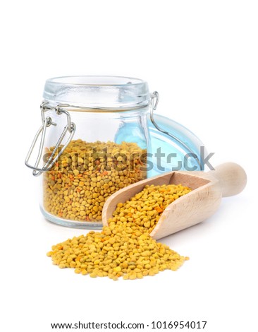 Bee pollen in a glass jar and a wooden shovel is isolated on a white background. Natural remedy for immunity enhancement. Beekeeping products. Apitherapy.