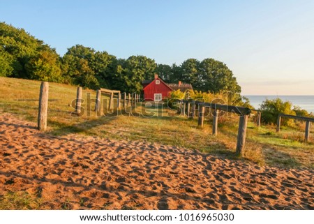 Part of the beach at Baltic sea in Skane Sweden in sunrise when fall and an old fisherman cottage in the background