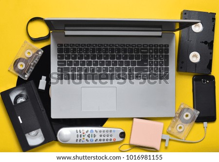 Modern digital gadgets, storage media, devaysy and obsolete analog media devices on a yellow paper background. Top view. Flat lay.