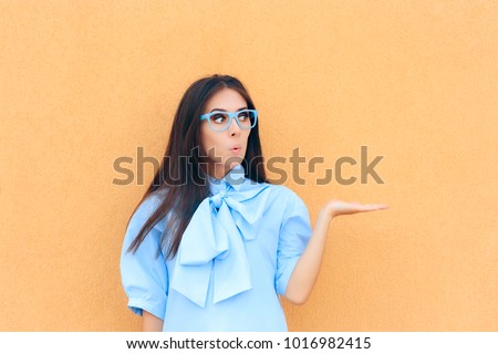Funny Beautiful Surprised Woman Holding Her Hand up for Presentation. Portrait of a cute girl with her pal up presenting something on yellow background
